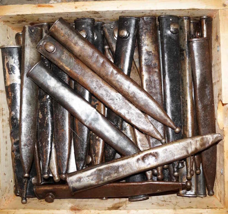 Loose M1935 bayonet scabbards in battered condition and covered with grease.